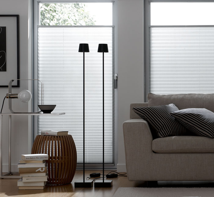 Modernes Wohnzimmer mit grauem Sofa und zwei schwarzen Stehlampen